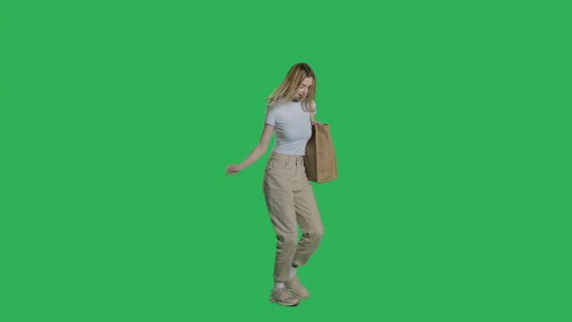 Young woman in casual clothes walks with shopping bag on a Green Screen, Chroma Key. 4k UHD perspective view isolated video.