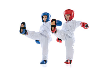Fototapeta na wymiar Studio shot of two little kids, boys, taekwondo athletes wearing doboks and sports uniforms isolated on white background.