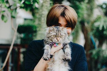 Close up of young Asian woman playing with her persian cat, human-animal relationships.