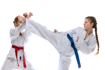 Close-up young girls, teens, taekwondo athletes practicing together isolated over white background. Concept of sport, education, skills © master1305