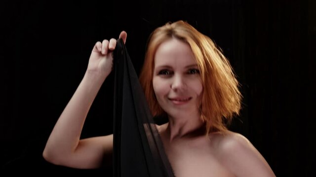 Seductive forty-year-old woman. Movement with a cloth in the dark. Pleasure, happy face.