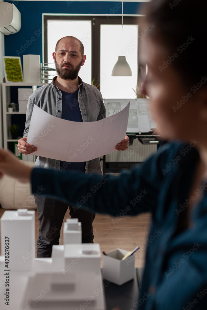 Poster standing architect holding blueprints thinking about architectural design working together with coll