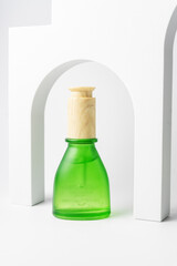 Green frosted glass bottle with facial essential oil or serum packaging on white background. Beauty cosmetic product for skincare concept. minimal and luxury style. Trendy showcase with podiums