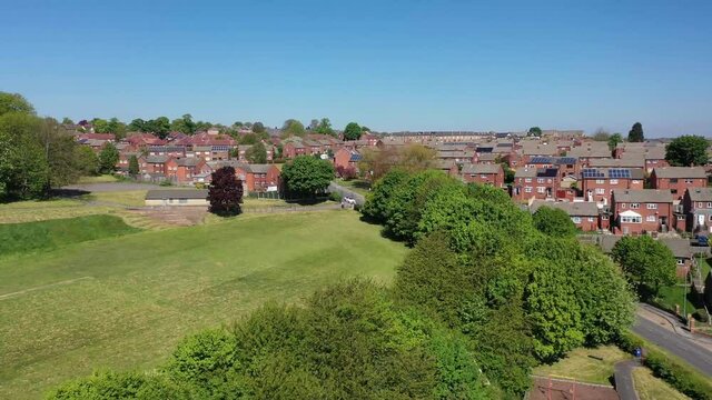 Aerial footage of the town of Batley in Yorkshire UK, showing a typical British housing estates with roads and streets, taken with a drone on a sunny day above the houses.