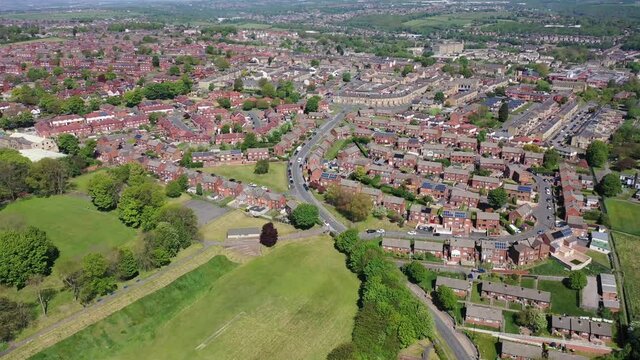 Aerial footage of the town of Batley in Wakefield West Yorkshire UK, showing a typical British housing estates with roads and streets, taken with a drone on a sunny day above the houses.