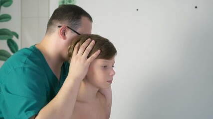Session of craniosacral therapy, cure of teen boy spine by a doctor therapist. The craniosacral therapist touches the boy on head and body and corrects of his spine posture at the hospital.
