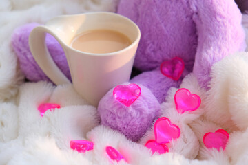 White cup and fluffy toy with  hearts. Birthday or Valentines Day concept