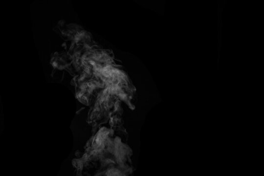Fragment of white hot curly steam smoke isolated on a black background, close-up. Create mystical photos.