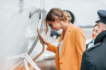 A young woman in yellow clothes is accompanied by an airline workers