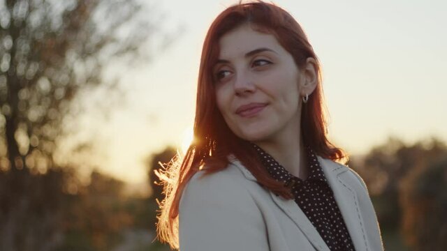 Primo piano di giovane ragazza con capelli rossi felice in campagna al tramonto