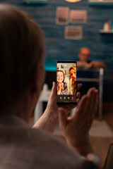 Close up of old woman holding smartphone with video call conference, talking to family members at home. Retired adult using technology for online communication sitting in wheelchair