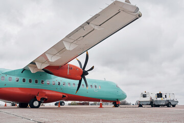 Orange and blue colored. Turboprop aircraft parked on the runway at daytime