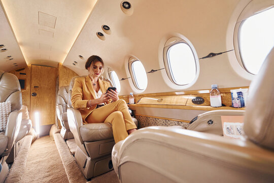 Woman in yellow clothes sits inside of private airplane