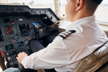 Fototapeta na wymiar Calm atmosphere. Pilot in formal wear sits in the cockpit and controls airplane
