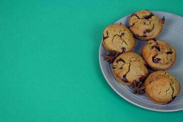 five muffins made of rice flour, yogurt, cherries and pumpkin oil lie on a gray plate on a green background, side view. gluten-free homemade cakes