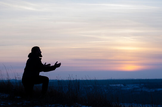 Prayer. Repentance. A man on his knees. Prayer. Silhouette of a man on a blue sky background. Kneeling Prayer to God. Glorification. Praising God. Christian. Zeal for God