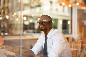 Businessman drinking coffee in cafe. Handsome African man using digital tablet while enjoy in fresh coffee