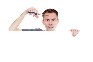 Young guy with scissors in hand on a white background. Copy space.