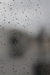 Rain drops on the glass in the spring afternoon. Close up of a window with rain drops falling down.The rain drops on household windows. Focus on rain drops. concept of sadness, frustration