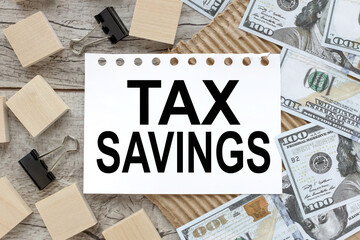 Tax Saving. text on white notebook pages near wood blocks. there are a lot of dollar bills on the...