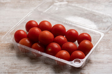 Cherry tomatoes in plastic containers on wooden desk