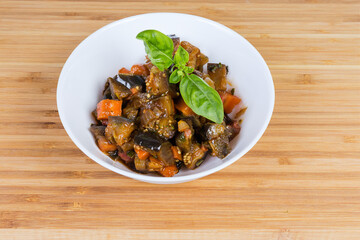 Chopped eggplants stewed with other vegetables in the white bowl
