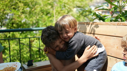 Two brothers hugging outside, smaller sibling embraces brother