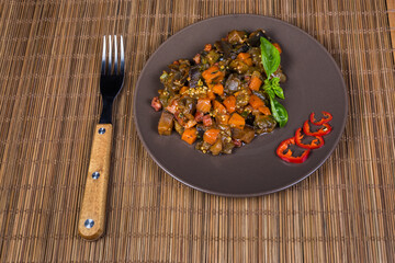 Chopped eggplants stewed with other vegetables on dish and fork