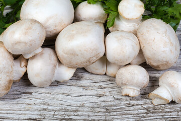 Uncooked button mushrooms on an old wooden surface close-up