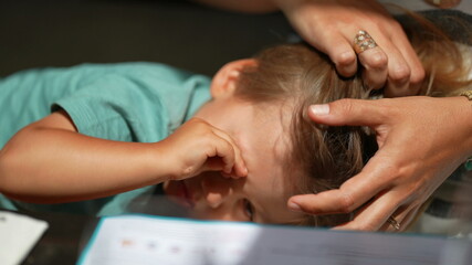 Obraz na płótnie Canvas Tired child rubbing eye with hand, mother caressing hair