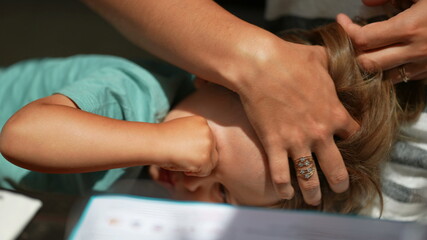 Naklejka premium Tired child rubbing eye with hand, mother caressing hair