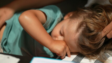 Obraz na płótnie Canvas Sleepy child rubbing eye with hand, kid lying down resting