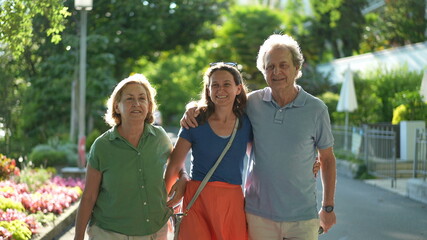 Naklejka premium Senior parents walking together with adult daughter outside talking in conversation