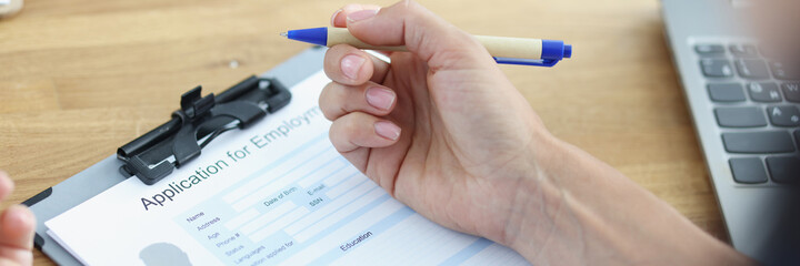 Woman holds pen and plans to fill out resume form for job