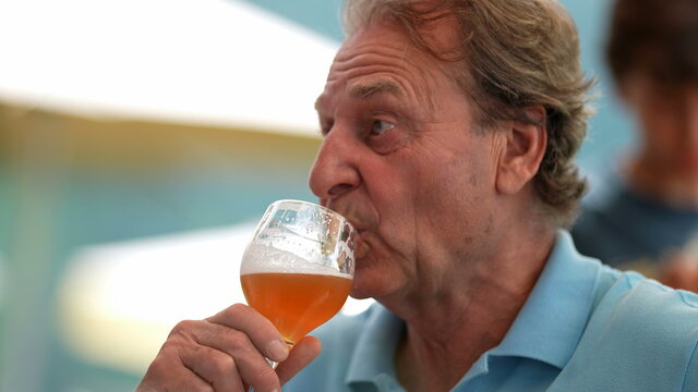 Senior person taking a sip of draft beer