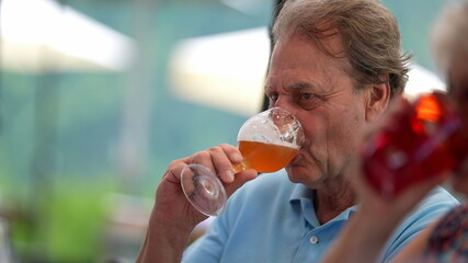 Senior man drinking beer with friends