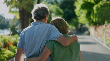 Romantic older husband putting arm around wife, senior couple walking