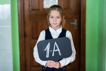 A cute girl is standing in the classroom with a grade 1 sign. School life