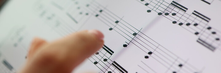 Woman finger points to musical notes. Classical music and music education