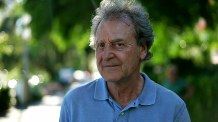 Pensive senior man walking outside in city green nature path