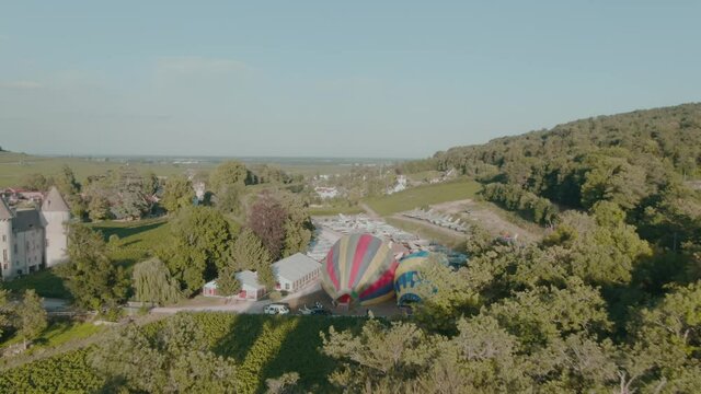 4k Aerial two hot air balloons inflating surrounded by old jet fighters and castle