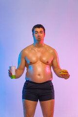 Fat man with burger and soda. Not sporty men drinking and eating hamburger isolated on pink background.