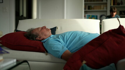 Obraz premium Older man lying in sofa resting. Senior person napping
