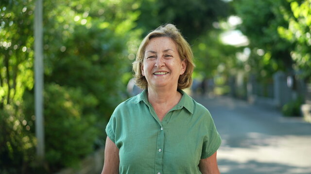 Happy senior woman walking forward smiling in city nature