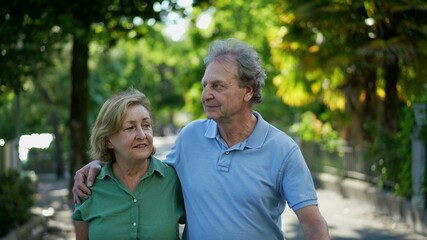 Happy senior couple in 60s walking embracing each other, old age relationship