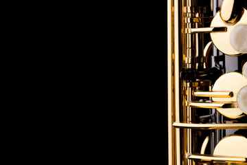 A black saxophone with gold plated keys on a black background