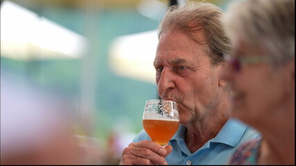 Happy older man drinking beer with friends