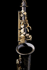A black saxophone with gold plated keys on a black background
