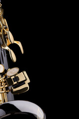 A black saxophone with gold plated keys on a black background