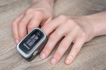 Woman with oximeter is measuring oxygen saturation and pulse